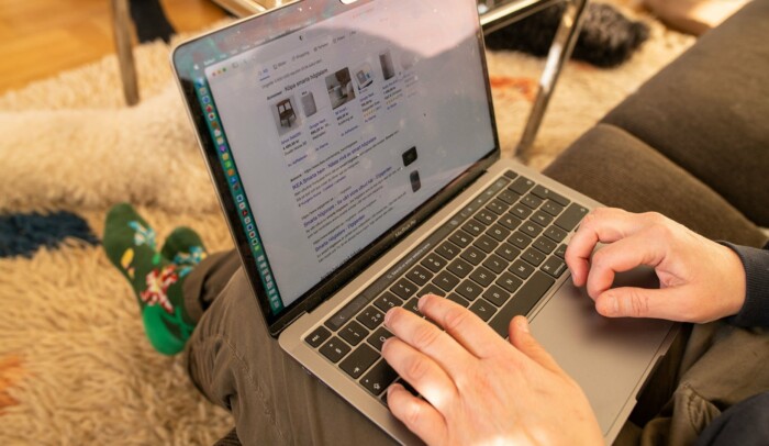 En person sitter med sin laptop i knät, på skärmen syns sökresultat.