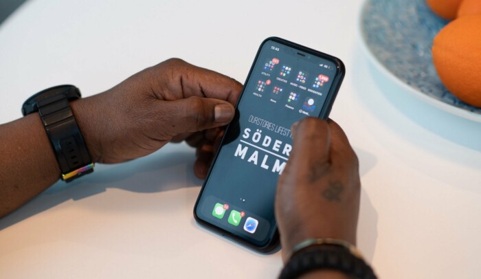 Händer som håller i en mobiltelefon, på skärmen syns olika appar.