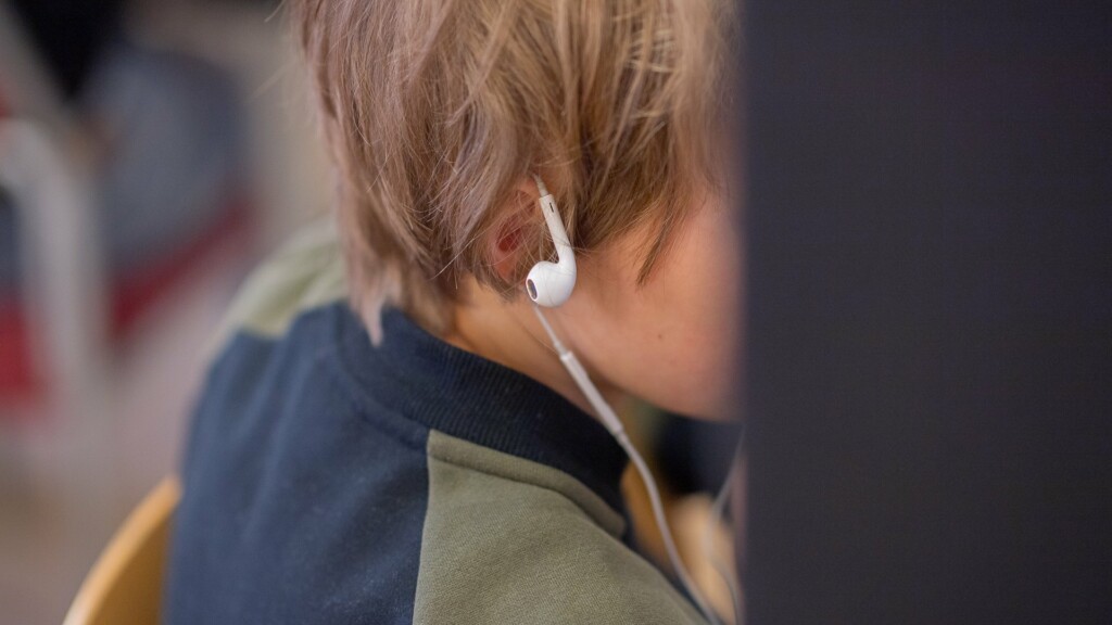 Profil på ett barn som har hörlurar hängandes över örat.