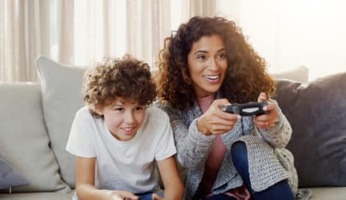 Kvinna och pojke spelar tv-spel i en soffa. gaming
