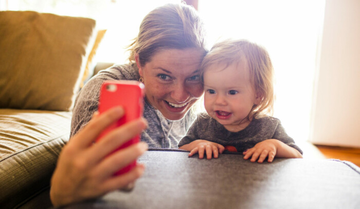 Kvinna och bebis tar en selfie med mobiltelefon.