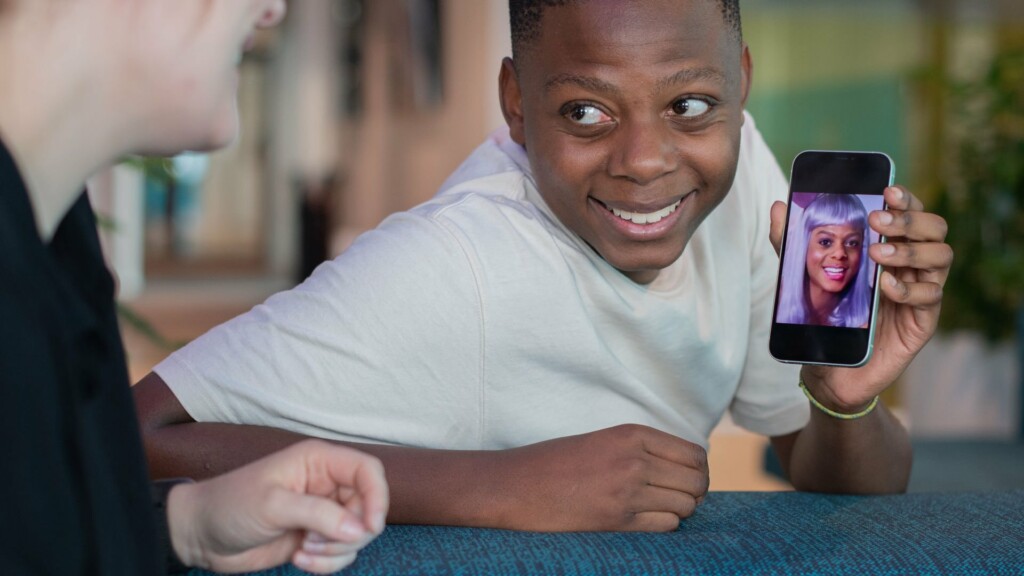 En ung kille visar upp en bild på sig själv med annan frisyr på mobilen.