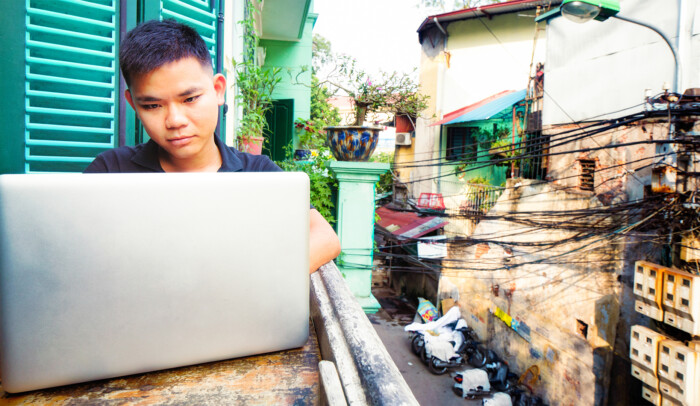 Kille från Asien som sitter i fönster och surfar på sin dator. internet mänsklig rättighet