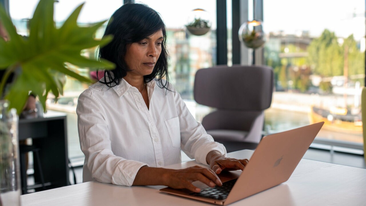Kvinna sitter vid ett bord med en laptop.