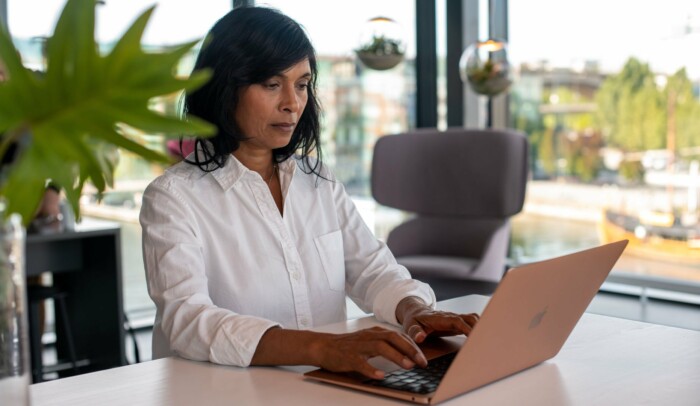 Kvinna sitter vid ett bord med en laptop.