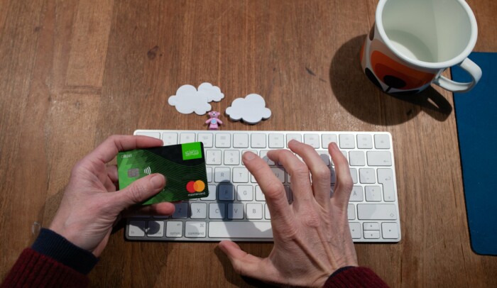 Händer som håller i ett betalkort och trycker på ett tangentbord