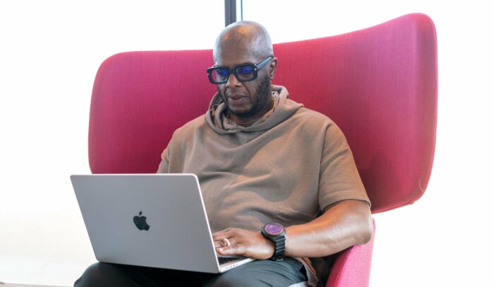 En man sitter i en fåtölj med en laptop i knät