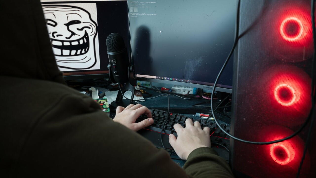 Person sitter vid sin dator, på skärmen syns ett otäckt ansikte