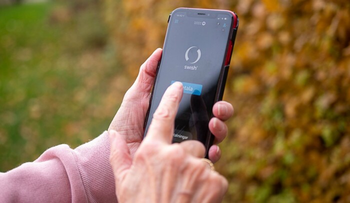 Hand som håller en mobil, på skärmen syns bank-id.