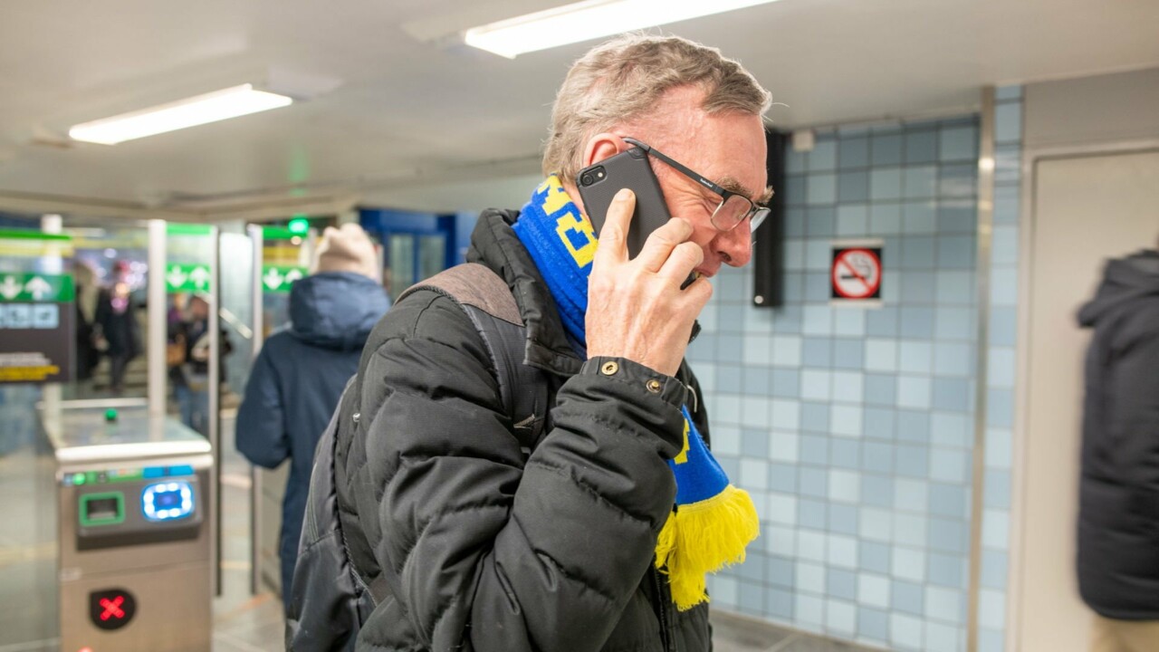 Äldre man pratar i mobiltelefon i tunnelbanan.