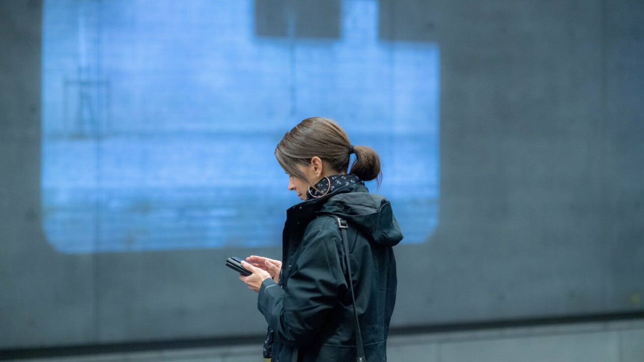 Kvinna i jacka tittar ner på en mobiltelefon.