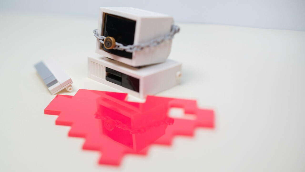 Ett pixelhjärta ligger på ett bord framför en dator i lego, datorn har ett hänglås runt sig.