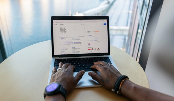 Händer på en laptop, på skärmen syns ett sökfält.