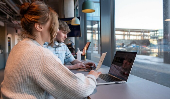 Två personer sitter på ett cafe med varsin laptop framför sig