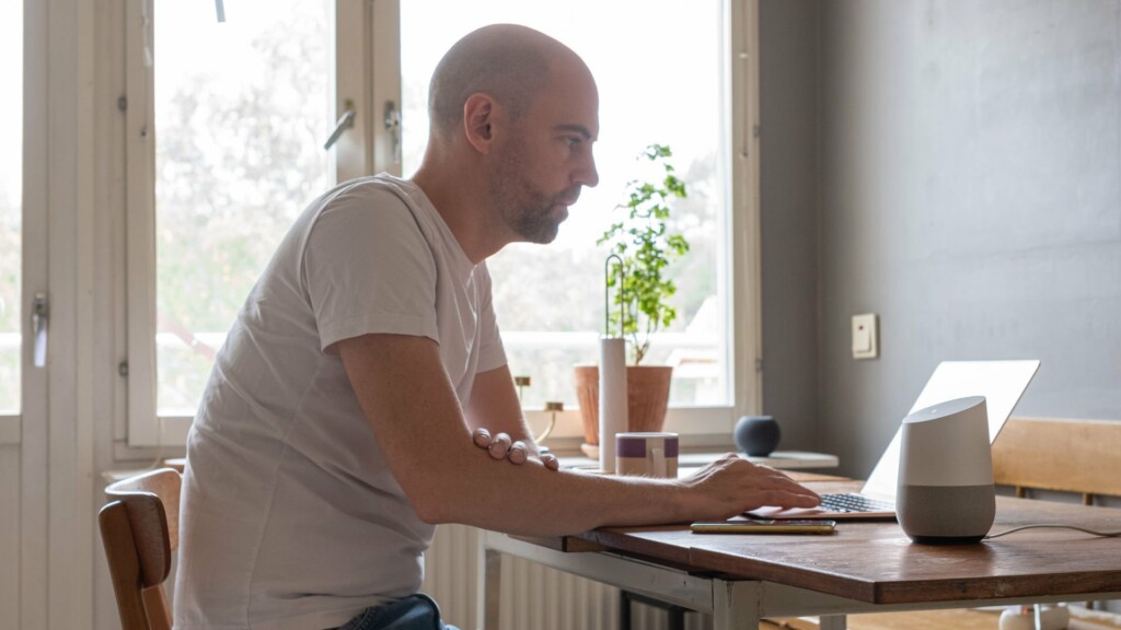 Man sitter vid köksbordet med en laptop.