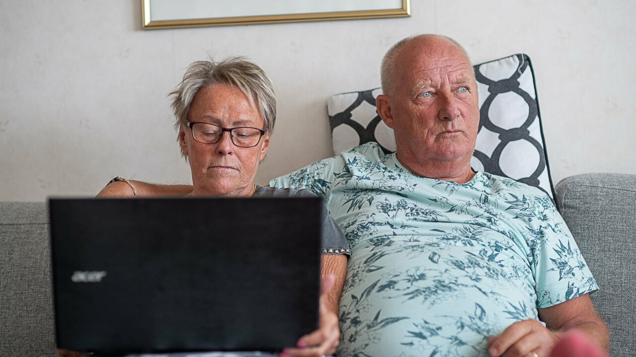 Man och kvinna sitter bredvid varandra i soffan, kvinnan har en laptop i knät.