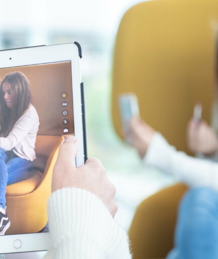 Kvinna fotograferar tonåring som sminkar sig med en iPad.