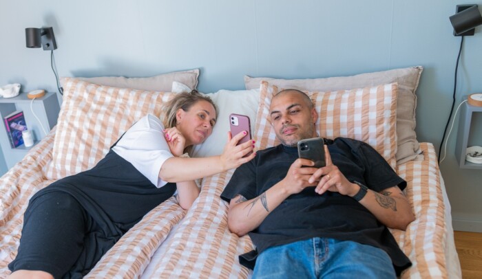 en man och en kvinna i en säng som kollar på en mobil