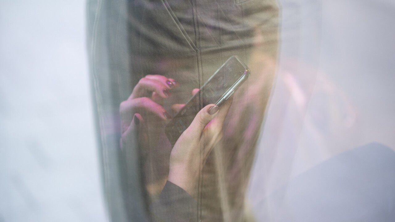 Reflektion av kvinnas händer som använder mobiltelefon.