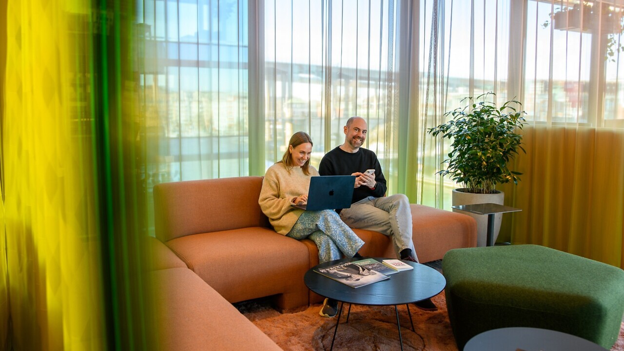 En man och en kvinna sitter i en soffa med en bärbar dator.