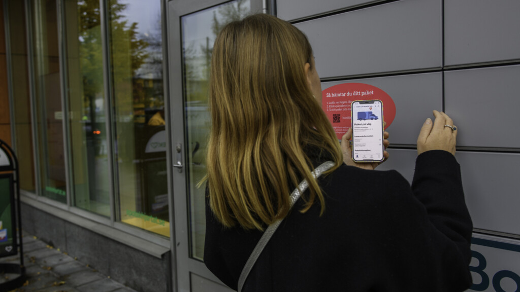En kvinna står vid ett postskåp och ska hämta ut ett dropshipping-paket.