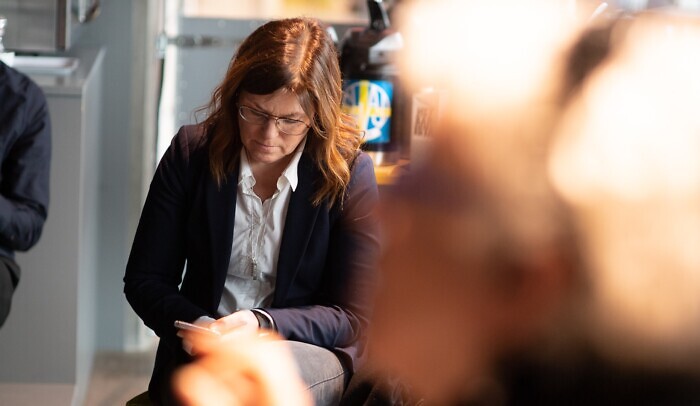 En kvinna sitter på en stol och tittar på sin mobiltelefon.