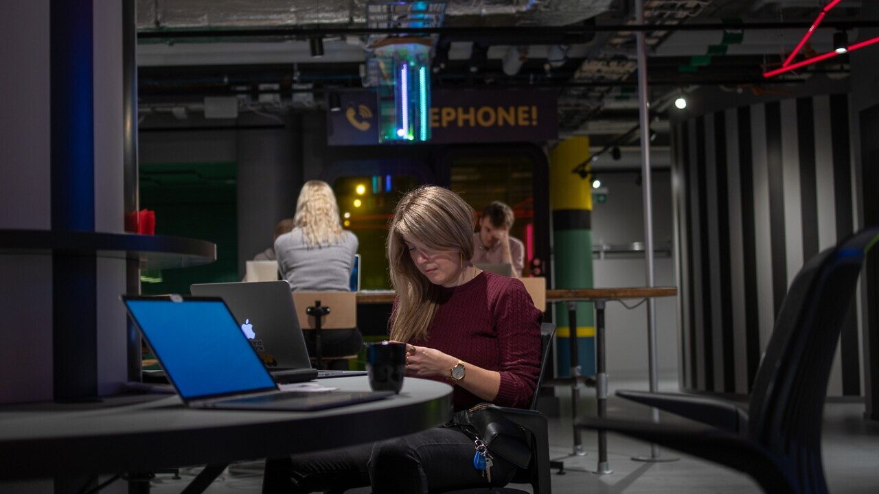 En kvinna sitter vid ett bord och använder en bärbar dator.