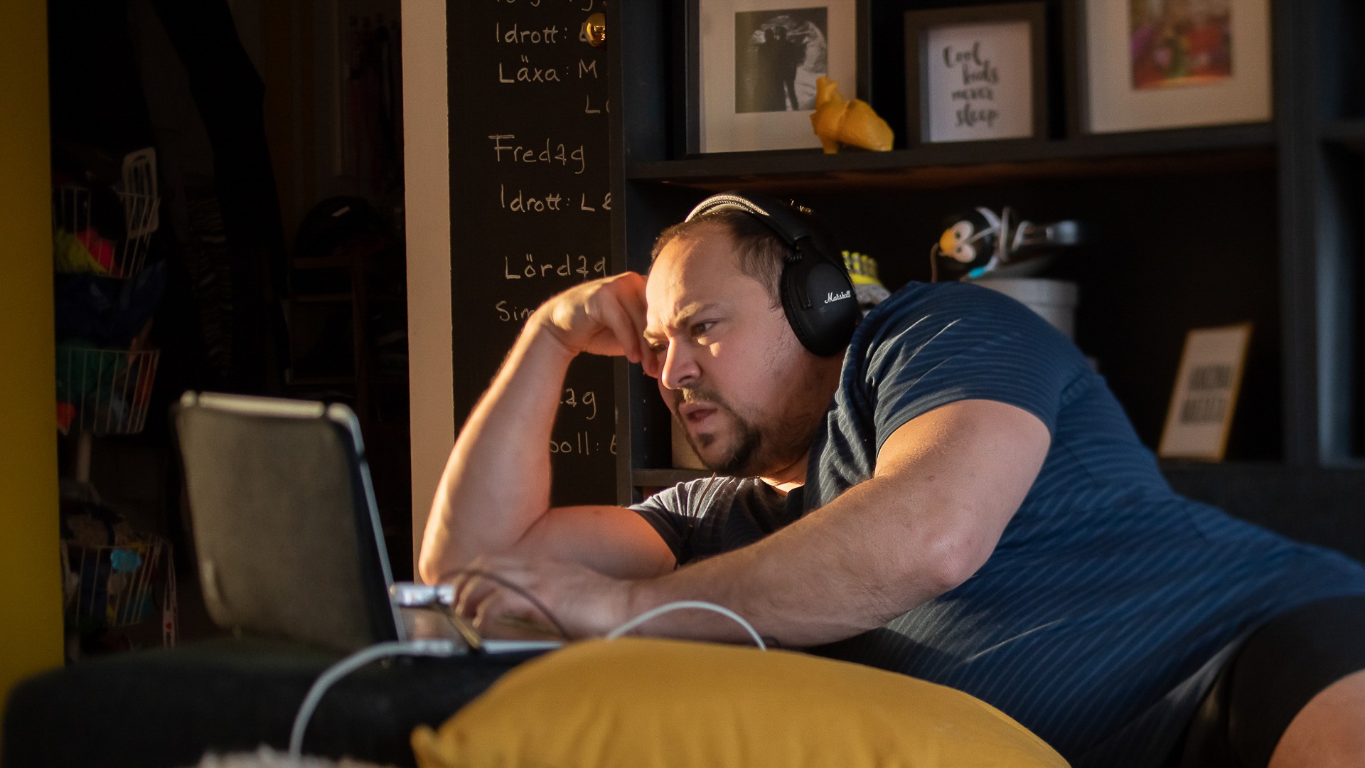 En man sitter i en soffa och använder en bärbar dator.