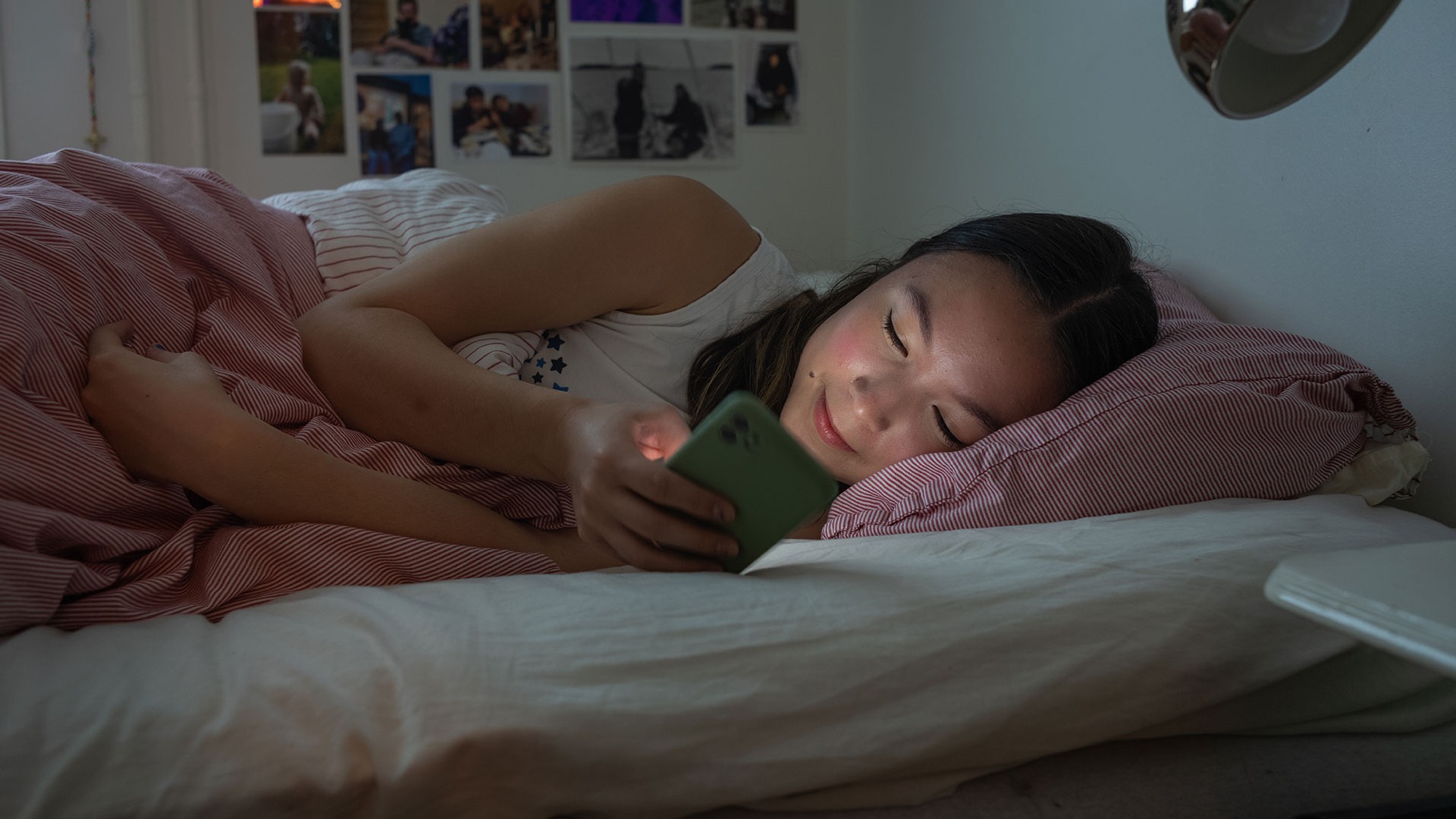 Flicka använder mobiltelefonen i sängen.
